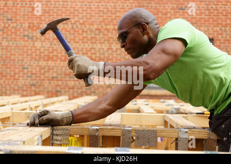 Black man hammering nail at construction site Stock Photo