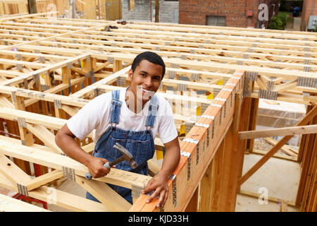 Portrait of mixed race man hammering nail at construction site Stock Photo
