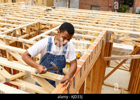 Mixed race man hammering nail at construction site Stock Photo