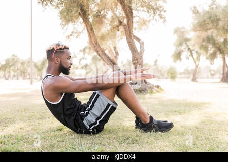 Black man doing sit-ups in park Stock Photo