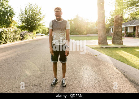 Black man standing on street in the neighborhood looking down Stock Photo