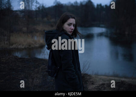 Portraits of serious Caucasian woman standing near river at night Stock Photo