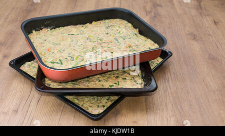 Three baking sheets with dough on wooden background. Preparation of salted Easter pie in HD ratio 16x9. Stock Photo