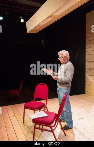 Hispanic man reading script on theater stage Stock Photo