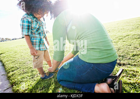 Mixed race mother tying shoe of son Stock Photo