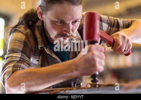 Caucasian man hammering leather Stock Photo