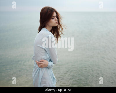 Troubled Caucasian woman standing near ocean Stock Photo