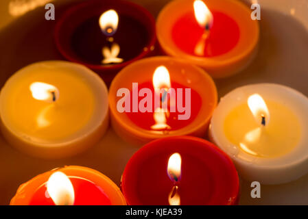 closeup to burning multicolored candles in darkness Stock Photo