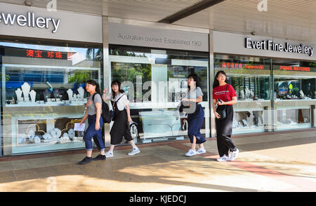 Smiling young Chinese tourists walking through the streets of Cairns, Far North Queensland, FNQ, QLD, Australia Stock Photo
