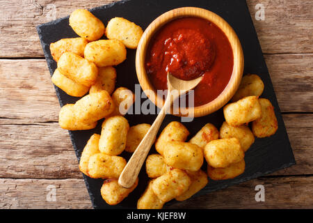 Homemade Tater Tots with tomato sauce close up on the table. Horizontal top view from above Stock Photo