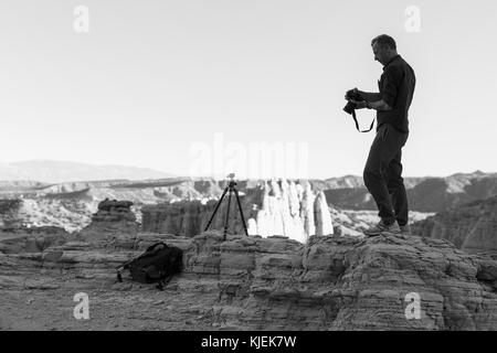 Caucasian photographer with tripod in desert Stock Photo