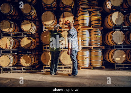 Caucasian men examining barrel in distillery Stock Photo