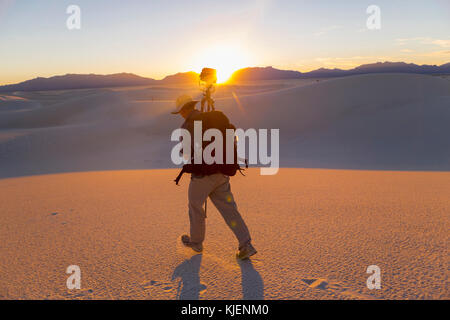 Caucasian man carrying camera and tripod in desert Stock Photo