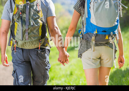 Couple carrying backpacks and holding hands Stock Photo