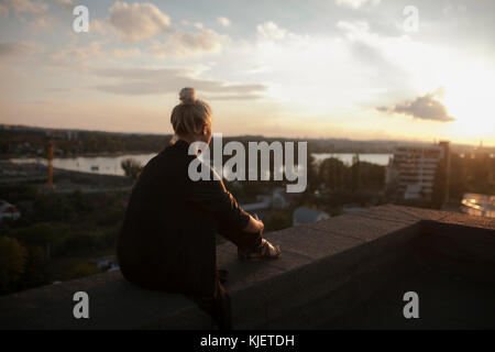 Caucasian woman on roof admiring scenic view of sunset Stock Photo