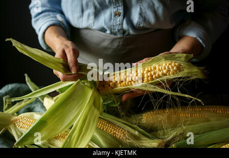 Close up of Caucasian woman shucking corn Stock Photo