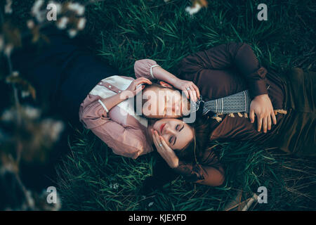 Caucasian couple laying in grass cheek to cheek Stock Photo
