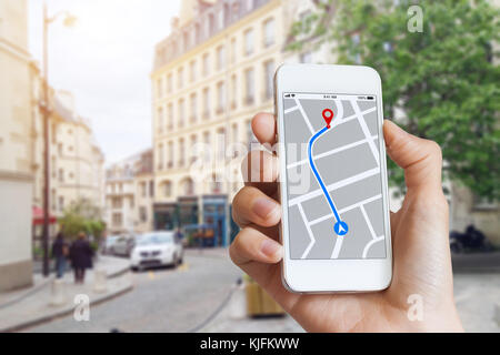 Tourist using GPS map navigation app on smartphone screen to get direction to destination address in the city streets, travel and technology Stock Photo