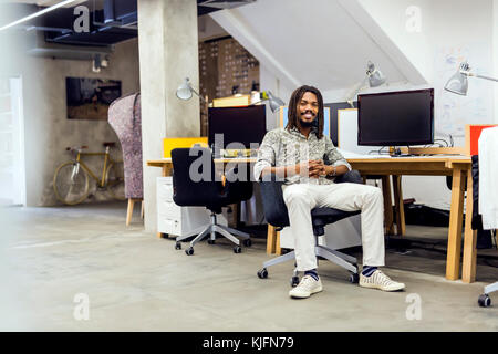 Handsome graphics designer sitting at a desk Stock Photo