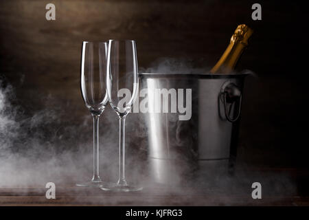 Photo of two wineglasses, iron bucket with bottle, steam on wooden background Stock Photo