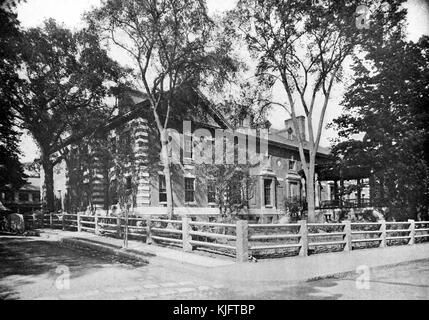 An exterior photograph of Harvard Union, it was built in 1900 to provide a space for students who didn't belong to other clubs at Harvard, a fence made from stone pillars and wood block off a small yard with trees in front of the building, it has been expanded and remodeled since it was built, eventually it was renamed the Barker Center, Cambridge, Massachusetts, Boston, Massachusetts, 1913. Stock Photo