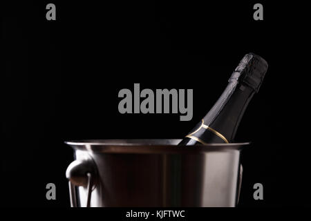 Image of bottle of wine in iron bucket on black background Stock Photo