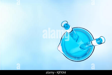 Chemical laboratory glassware with beaker and flasks filled with stirring rod and colored liquid. Top view. Stock Photo
