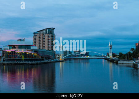 Image of the Lowry Theatre and Lowry Art Gallery taken from the Manchester Ship Canal in the early evening with the Millennium Bridge in background. Stock Photo