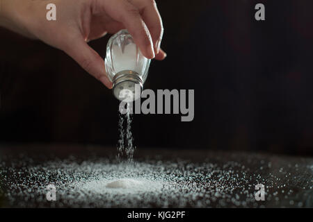 Adding salt. Backlight to salt from salt shaker. Close up Stock Photo