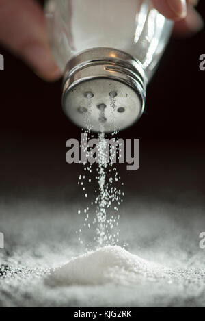 Adding salt. Backlight to salt from salt shaker. Close up Stock Photo