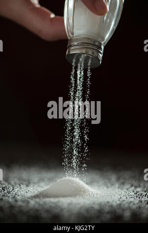 Adding salt. Backlight to salt from salt shaker. Close up Stock Photo