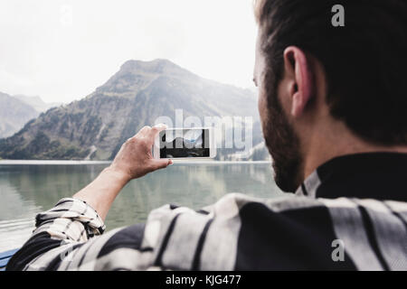 Austria, Tyrol, Alps, man taking cell phone picture of mountainscape Stock Photo