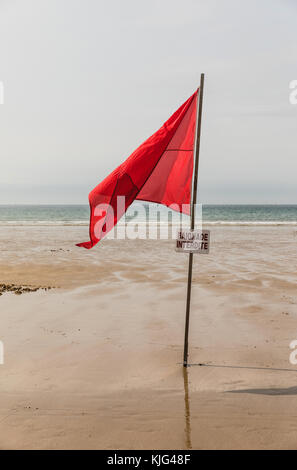 Red flag on the beach with a no swimming sign in French Stock Photo