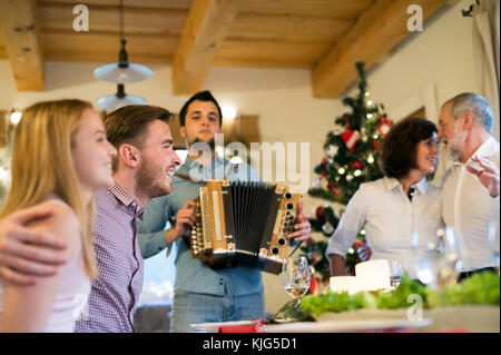 Young man playing accordion for family at Christmas Stock Photo