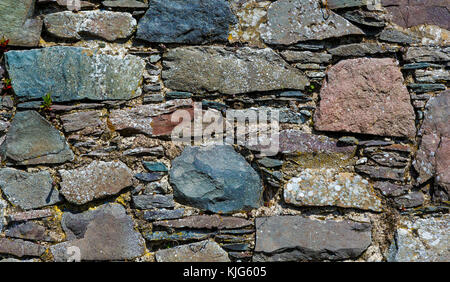 Dry stone wall made up from multicoloured rocks and slates. Stock Photo