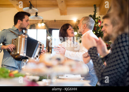 Young man playing accordion for family at Christmas Stock Photo