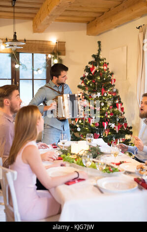 Young man playing accordion at Christmas dinner table Stock Photo