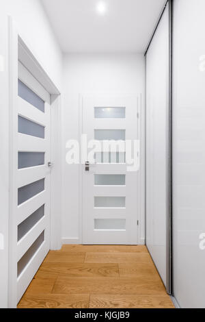 Hallway with white doors, wooden floor and big wardrobe Stock Photo