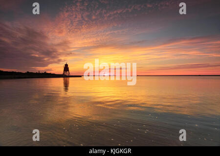 Herd Groyne lighthouse in South Shields at the mouth of the River Tyne,  on a summers morning as the sky bursts forth with colour. Stock Photo