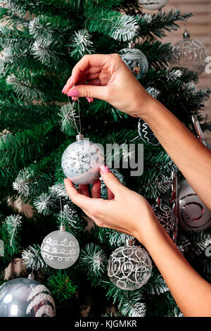 Woman hanging silver Christmas ball on fir tree, holiday concept Stock Photo