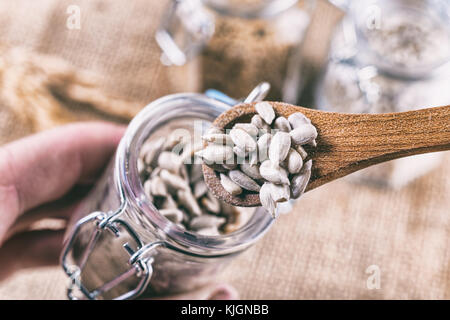 Sunflower seeds in wooden spoon on top of a jar Stock Photo