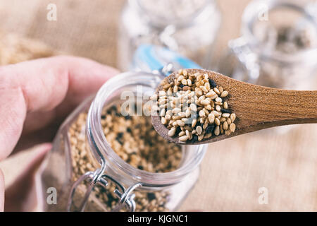 Sesame seeds in wooden spoon on top of a jar Stock Photo