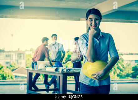 Portrait of Happy professional construction engineer woman holding the blueprint and wearing the safety helmet and glasses at the building site place  Stock Photo