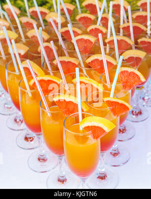 Orange juice cocktail in a flute glasses and slice of fresh orange with draw on white table,closed picture. Stock Photo