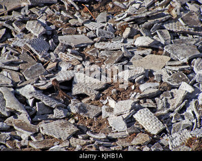 Pieces of old crashed asbestos roof tiles sheets on ground close up Stock Photo