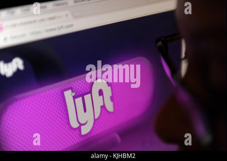 A woman looks at the Lyft website on a computer screen. Lyft is a ride sharing company Stock Photo