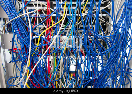 A computer network server cabinet with a mess of tangled blue coloured cables. Stock Photo