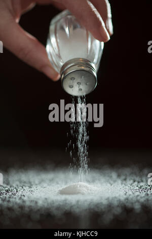 Adding salt. Backlight to salt from salt shaker. Close up Stock Photo