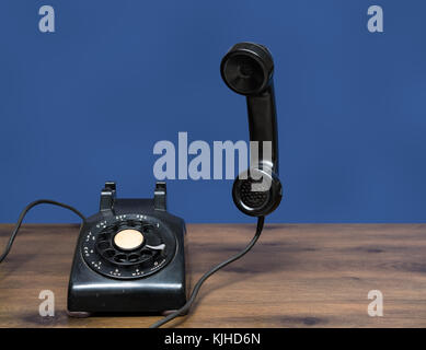 Antique old rotary dial telephone on wooden desk Stock Photo