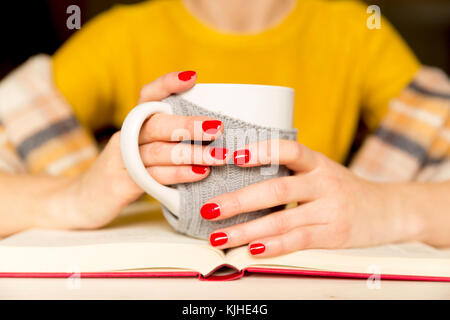 Beautiful women reading a book and drinking coffee with scarf at cozy home Stock Photo